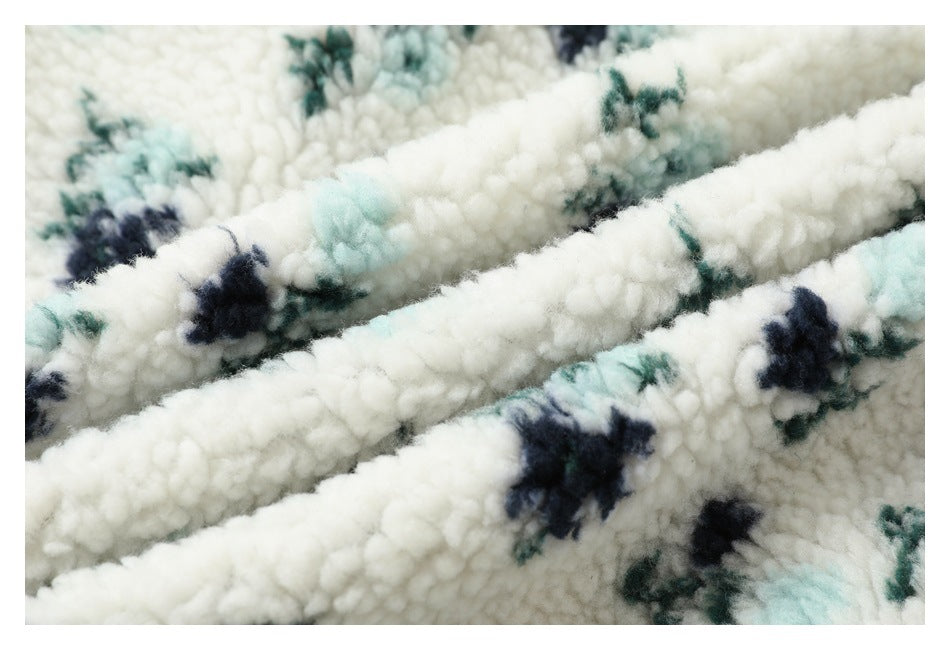 Macro view of soft ivory plush fabric with navy, teal, and pale aqua floral motifs, folded into ridges.