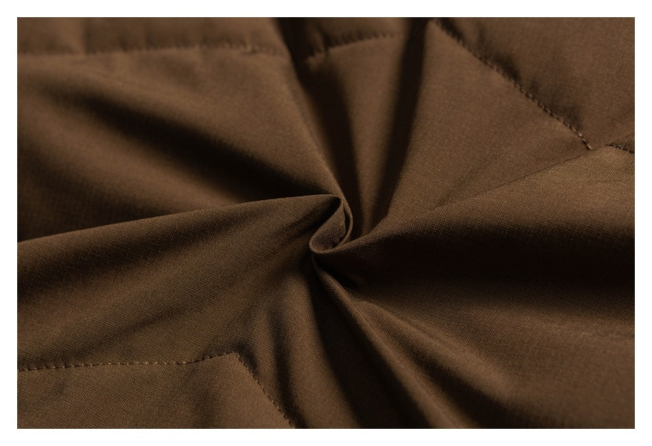 Close-up of brown jacket fabric gathered into folds, with stitched seams visible.
