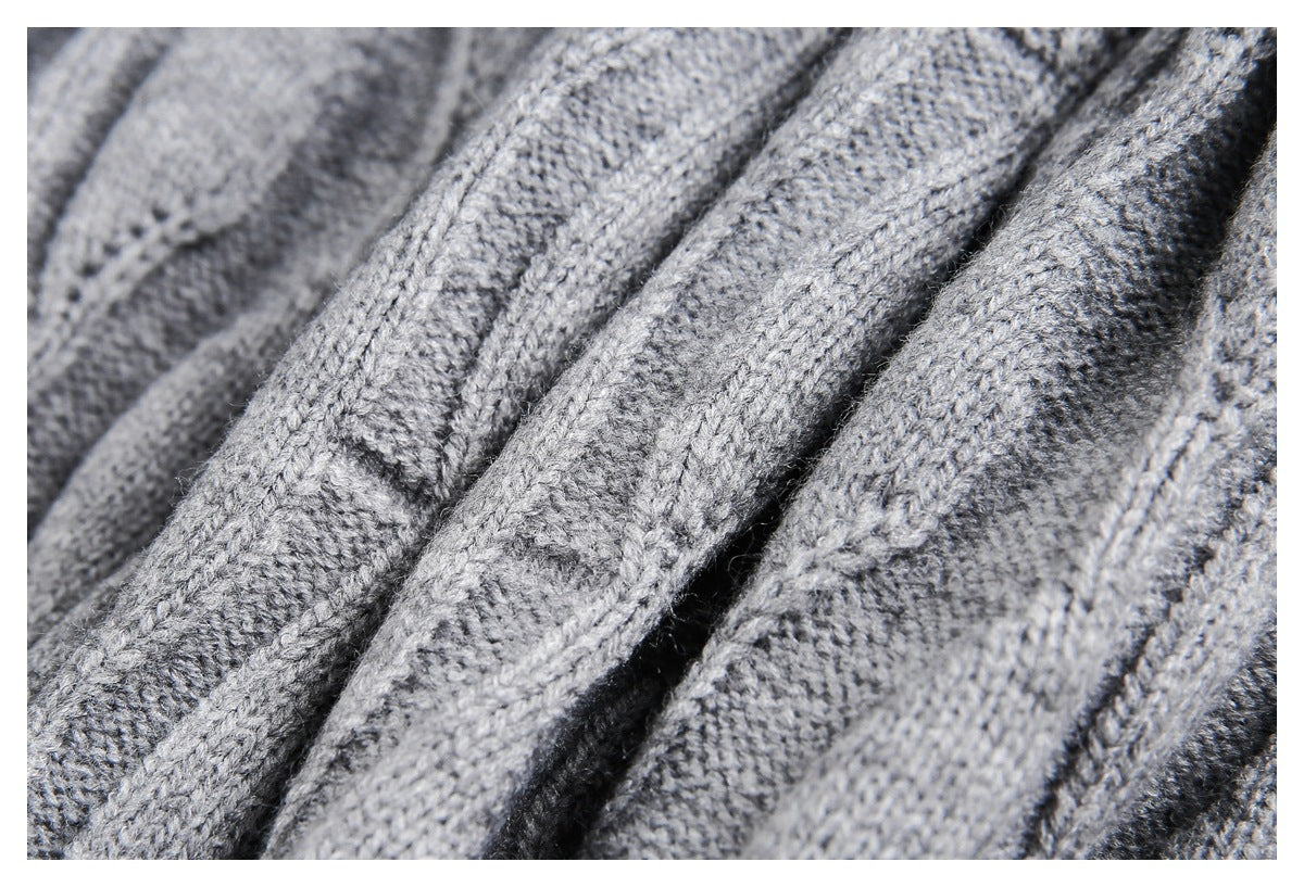 Macro view of gray sweater knit stitches and raised cable-knit ridges.