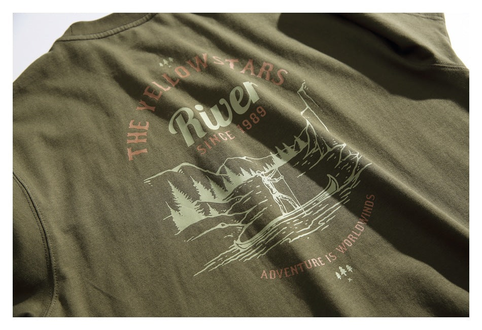 Close-up of an olive green T-shirt back with a vintage-style mountain and river graphic in pale and muted red print.