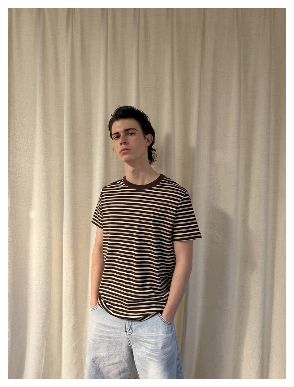 Model wearing a dark brown and cream striped crew-neck T-shirt, shown from the front with light denim shorts.