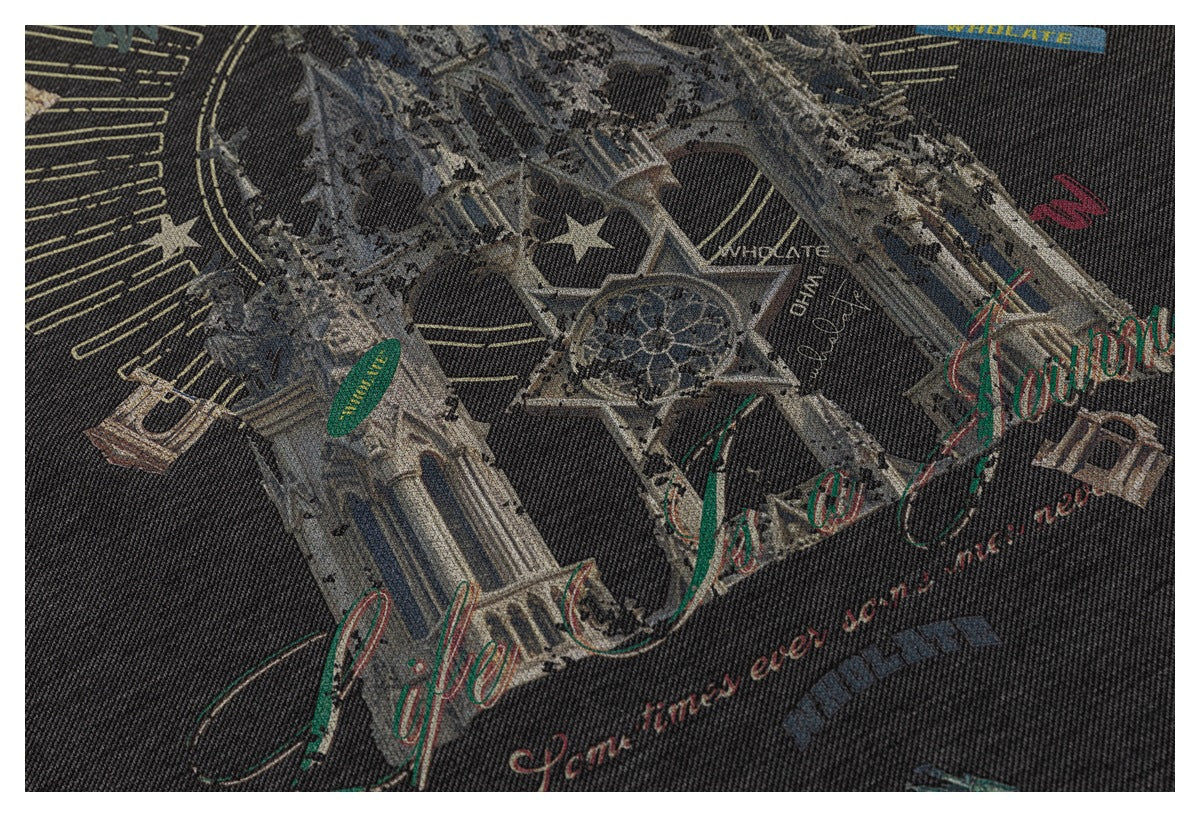 Close-up of dark fabric with a multicolor city-landmark graphic and decorative lettering.