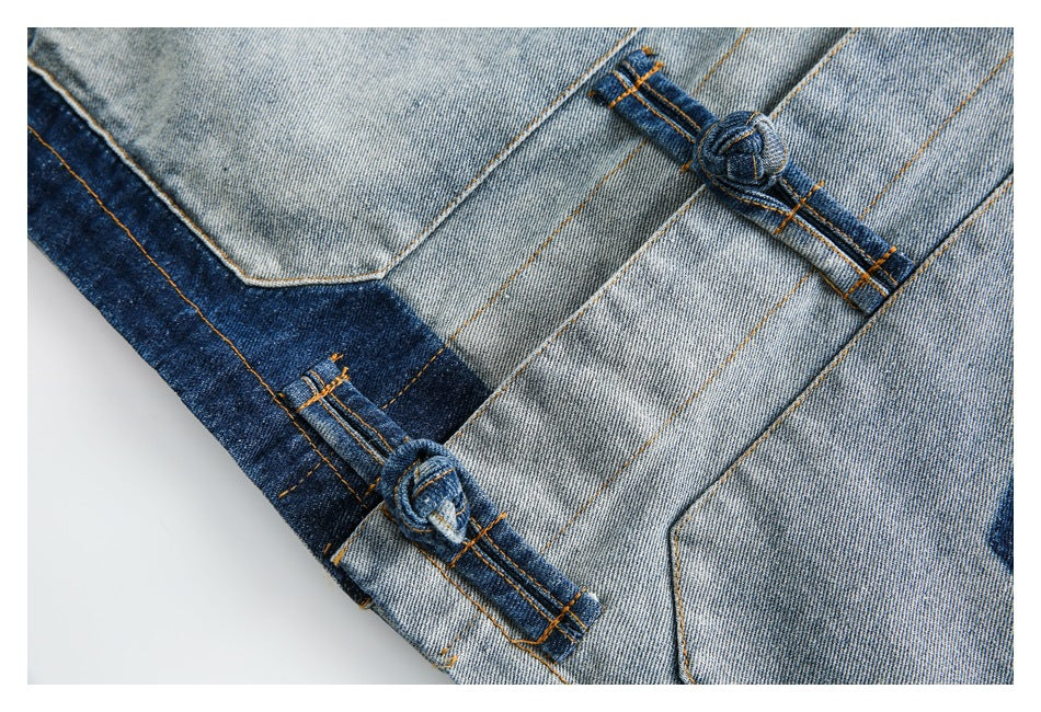 Close-up of light and dark blue denim panels with orange topstitching and knotted denim loop details.