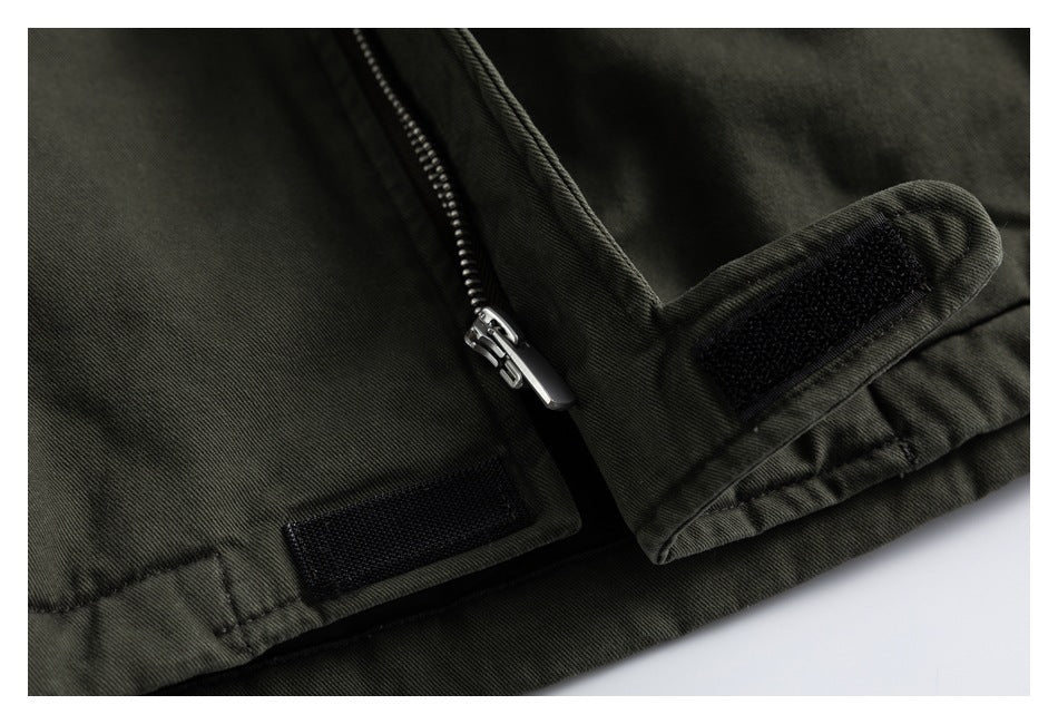 Close-up of a metal zipper and black hook-and-loop tabs on an olive-gray jacket.