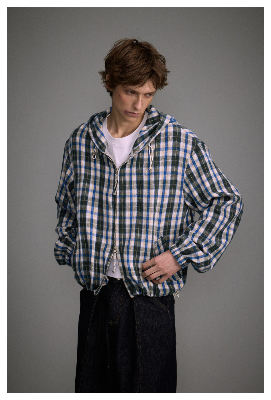 Model wearing a blue, black, and cream plaid hooded zip jacket over a white T-shirt.