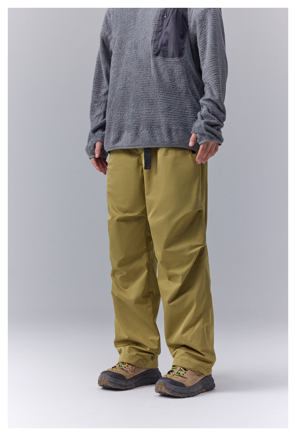 Front view of a person wearing loose olive pants with a gray pullover.