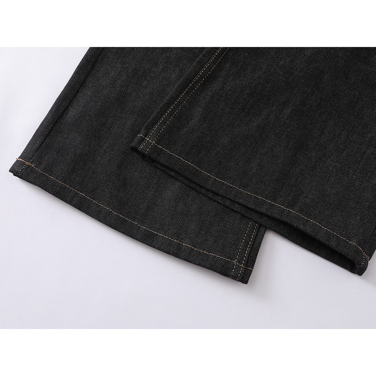 Close-up of the black jeans' wide-leg hems and tan contrast stitching.