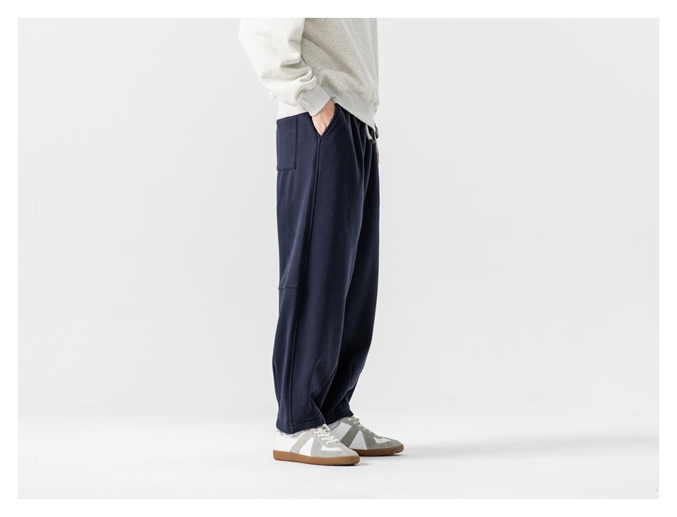 Side view of a model wearing loose navy joggers, showing the side seam and upper patch pocket.