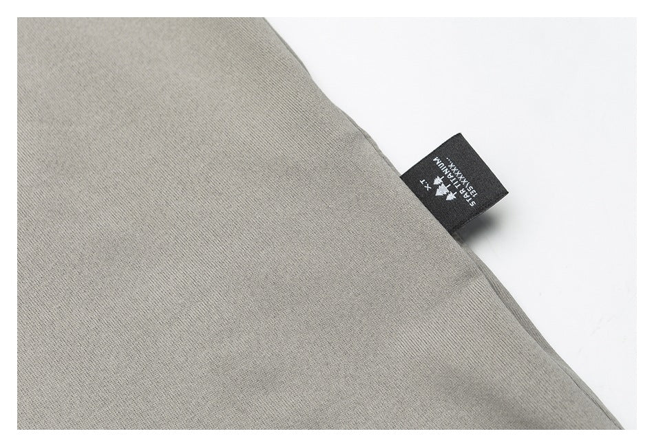Close-up of gray fabric with a small black woven label bearing white lettering.