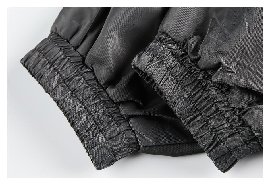 Close-up of two gathered elasticized cuffs on dark gray garment fabric.