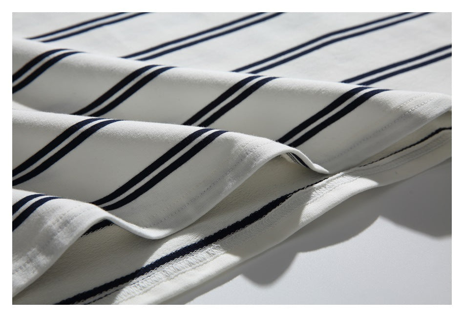 Close-up of white fabric with parallel navy stripes and a stitched hem.