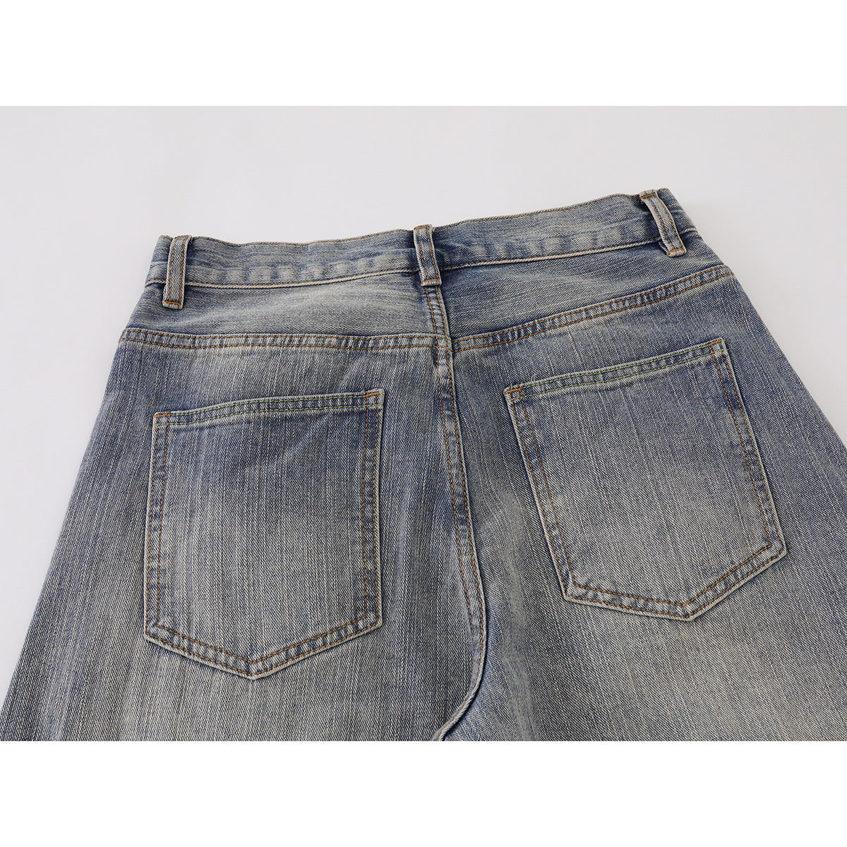 Close-up back view of washed blue-gray jeans with two patch pockets and a center seam.