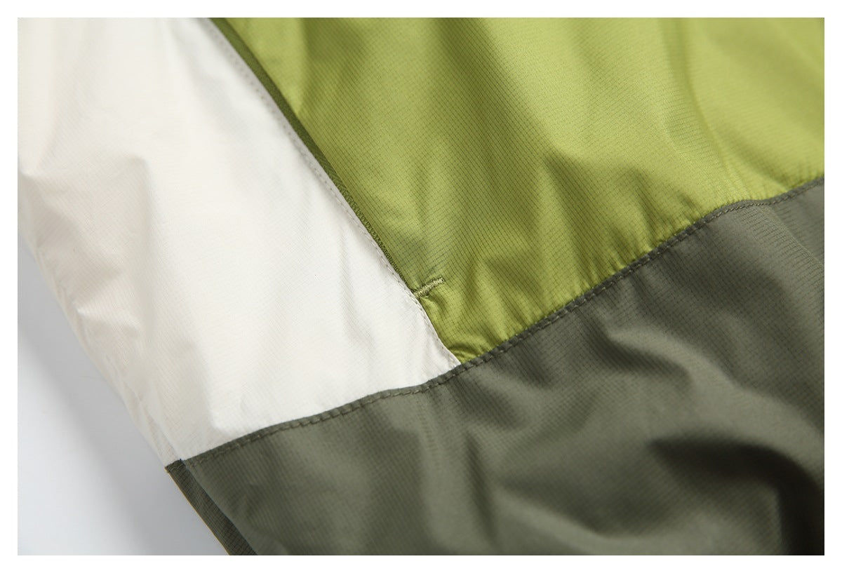 Close-up of stitched olive-green, white, and charcoal-gray color-block panels on a jacket.