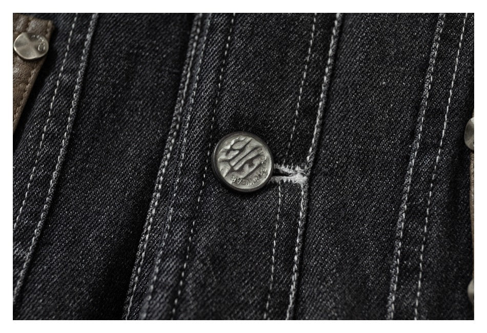 Close-up of a metal button and contrast-stitched seams on black denim.