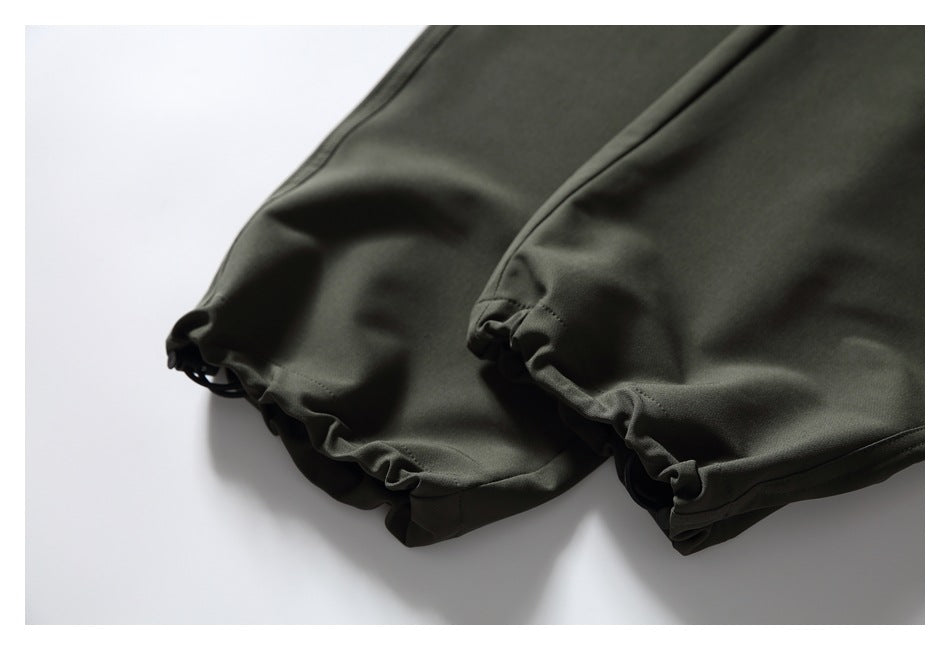 Close-up of gathered elastic cuffs on dark olive pants.
