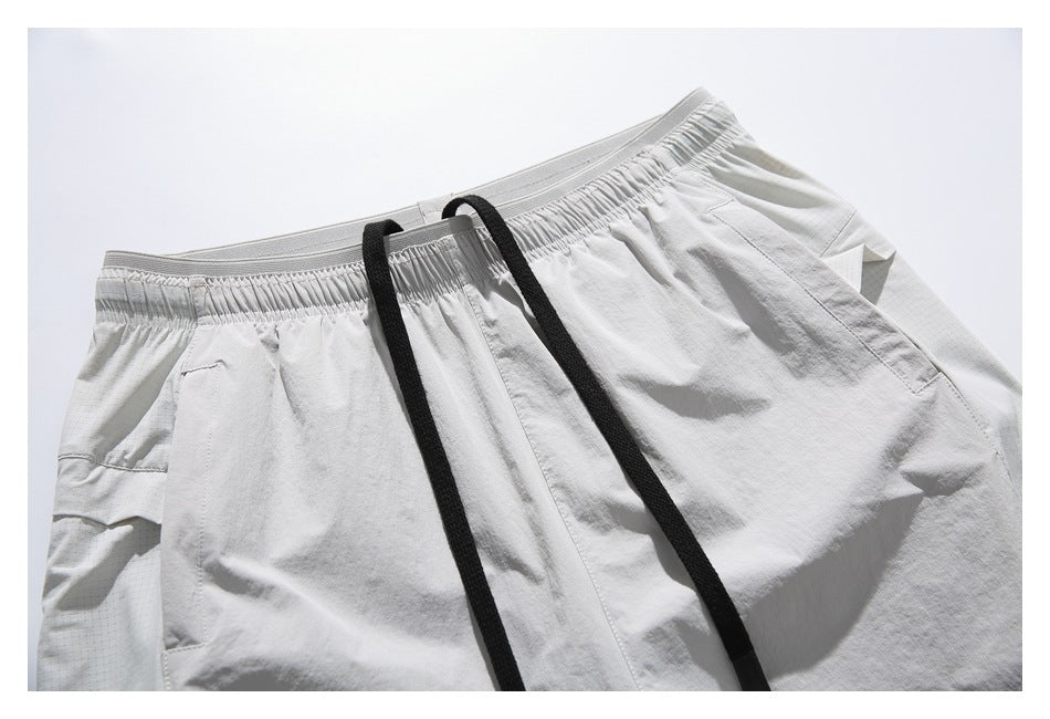 Close-up of white shorts with an elastic waistband, long black drawstrings, and angled side pockets.