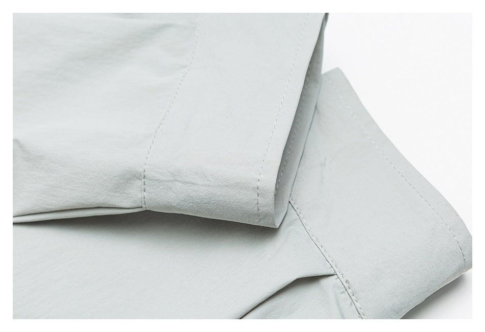 Close-up of pale gray fabric with folded, double-stitched edges.