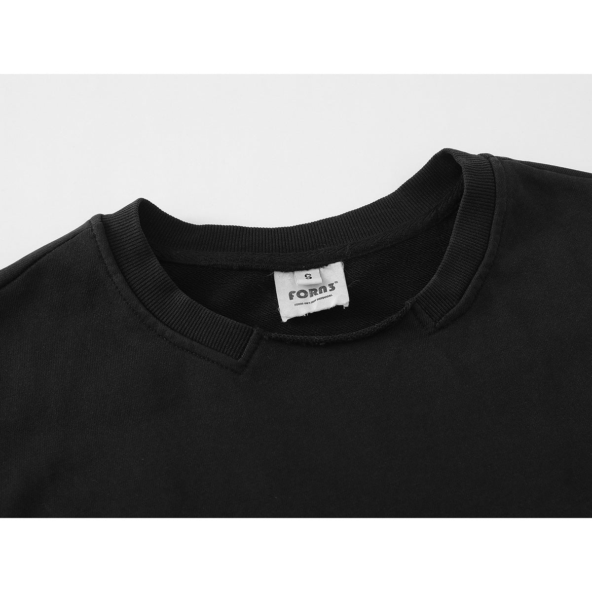 Close-up of a black sweatshirt neckline with ribbed collar and a white sewn-in brand label.