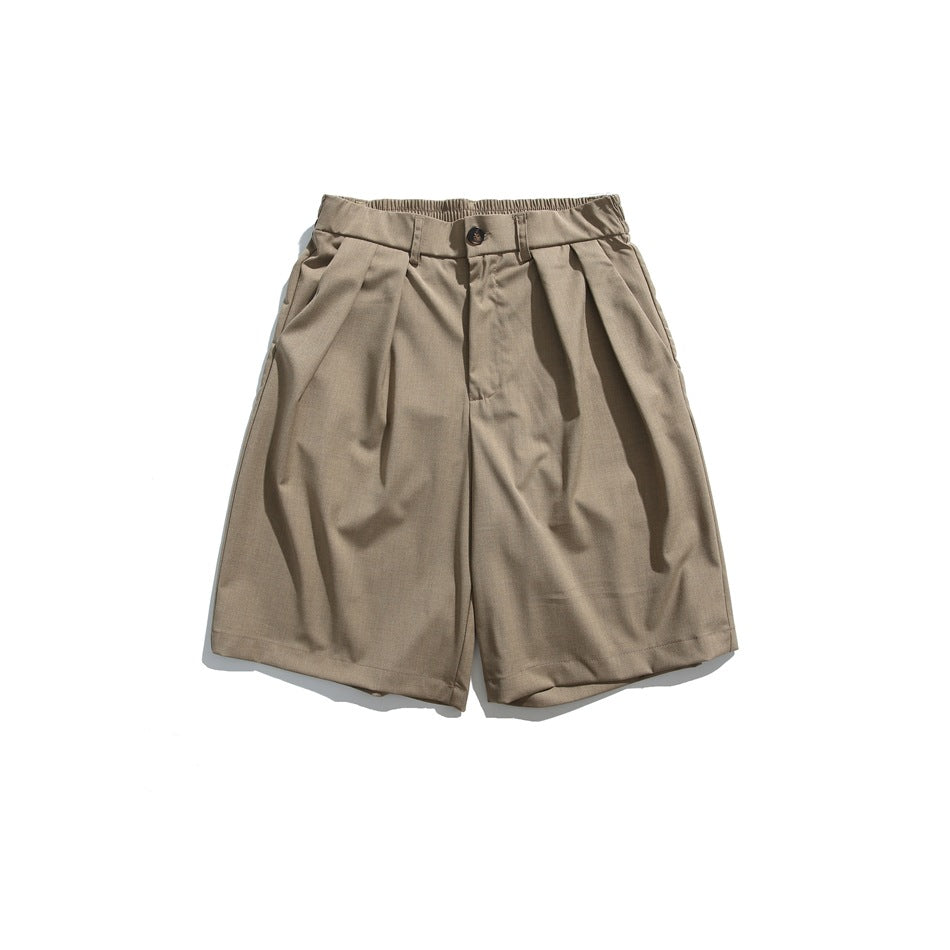 Front view of taupe pleated shorts with a button closure, belt loops, and side pockets.