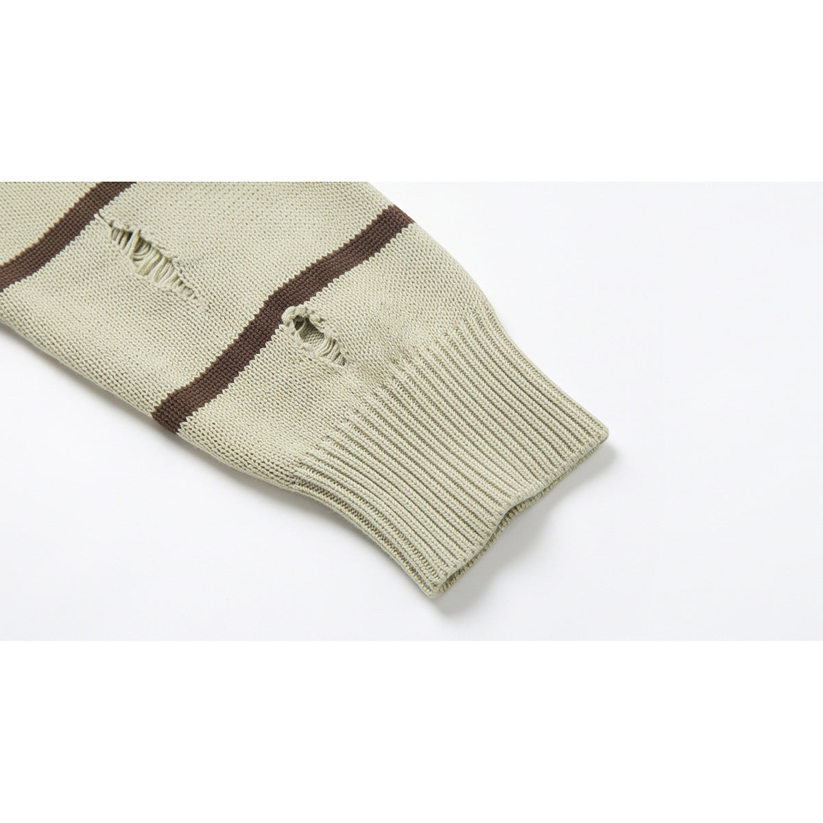 Close-up of a pale beige sweater sleeve with brown stripes, distressed holes, and a ribbed cuff.