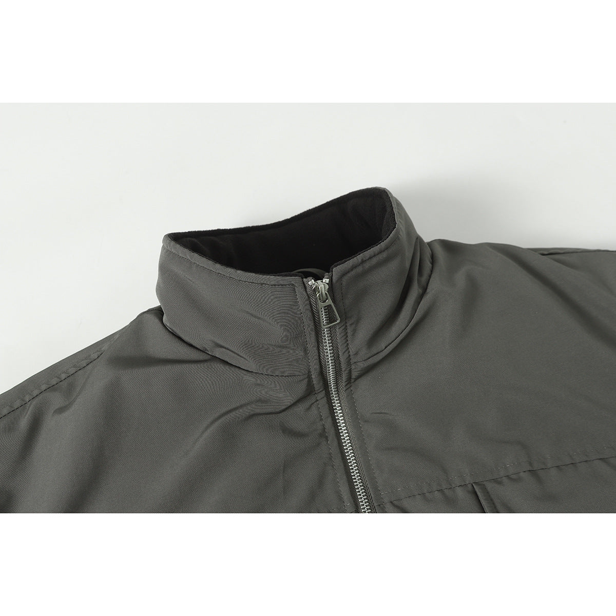 Close-up of a dark gray jacket's stand collar and silver front zipper.