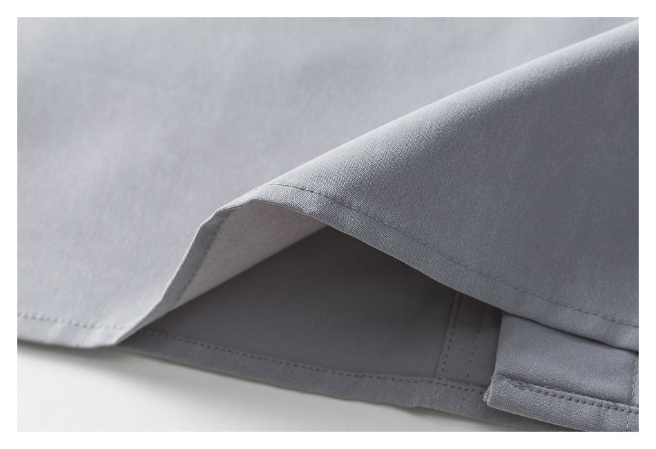 Close-up of a light gray garment hem with a slit and layered stitching.