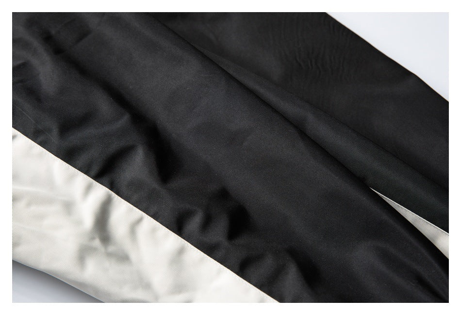 Close-up of black garment fabric with a contrasting beige panel and stitched seam.