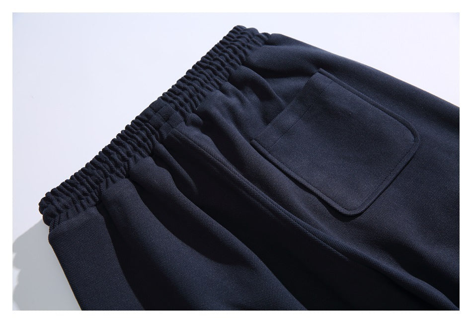 Close-up of dark navy pants showing a gathered elastic waistband and a rectangular patch pocket.
