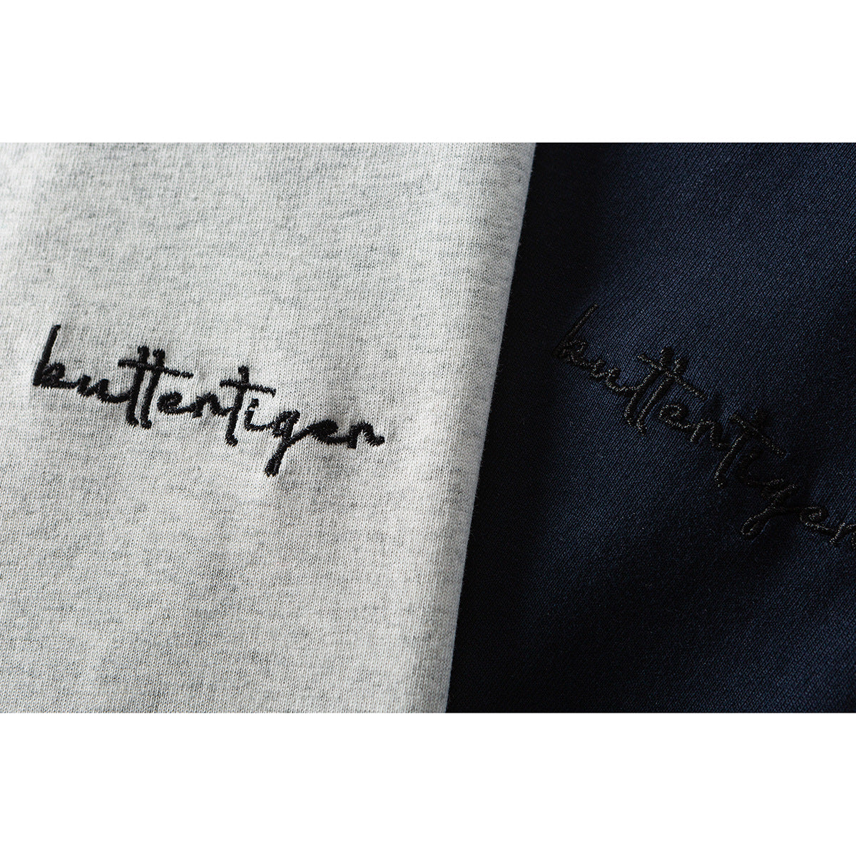Close-up of black script embroidery on heather-gray and navy shirt fabric.