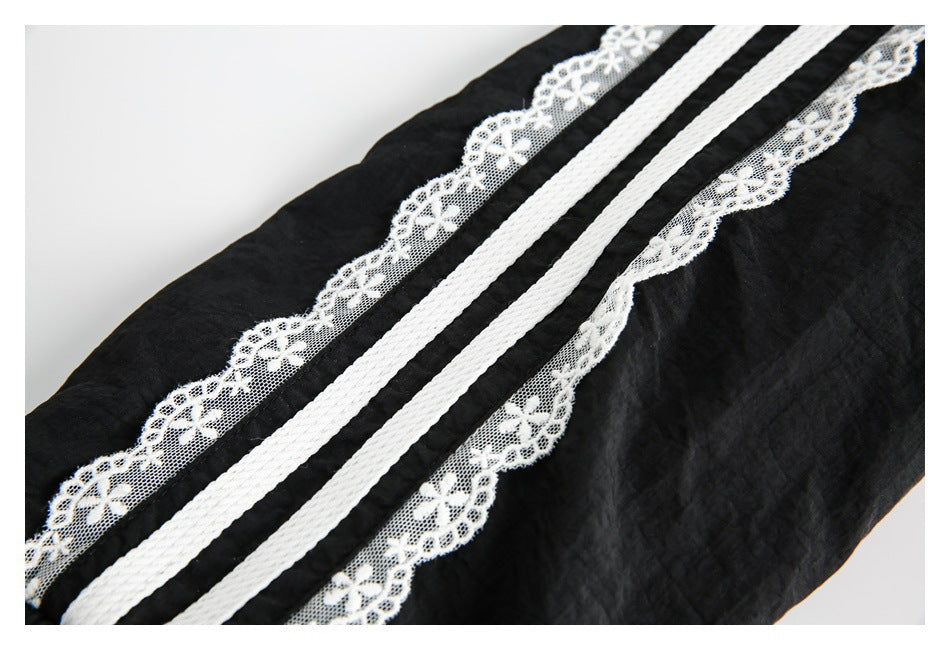 Diagonal close-up of black fabric with white floral lace and parallel braided stripe trim.
