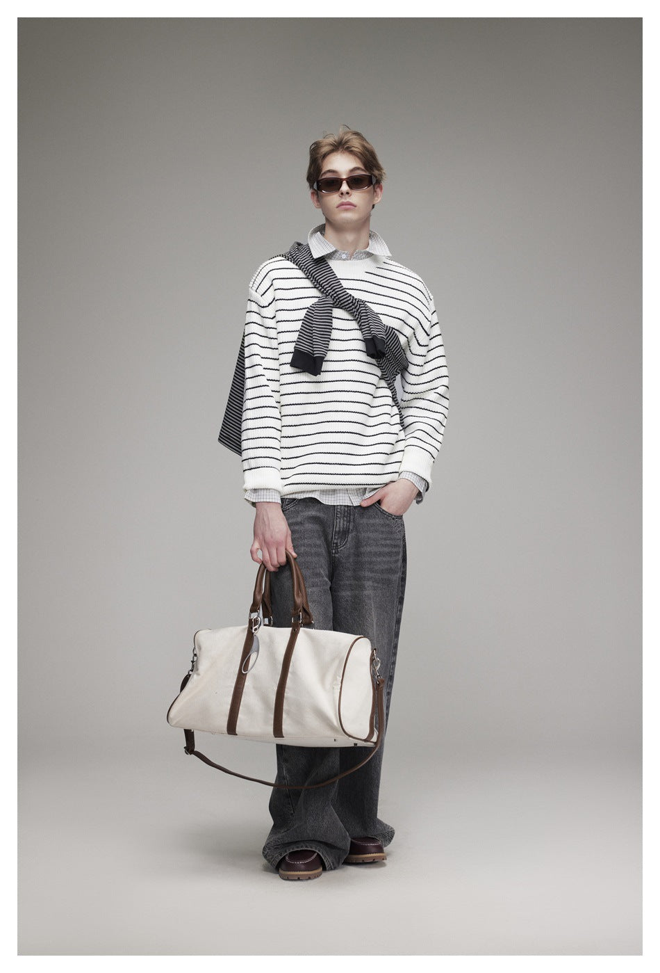 Full-length view of a model wearing an ivory sweater with thin black stripes and a dark striped scarf.