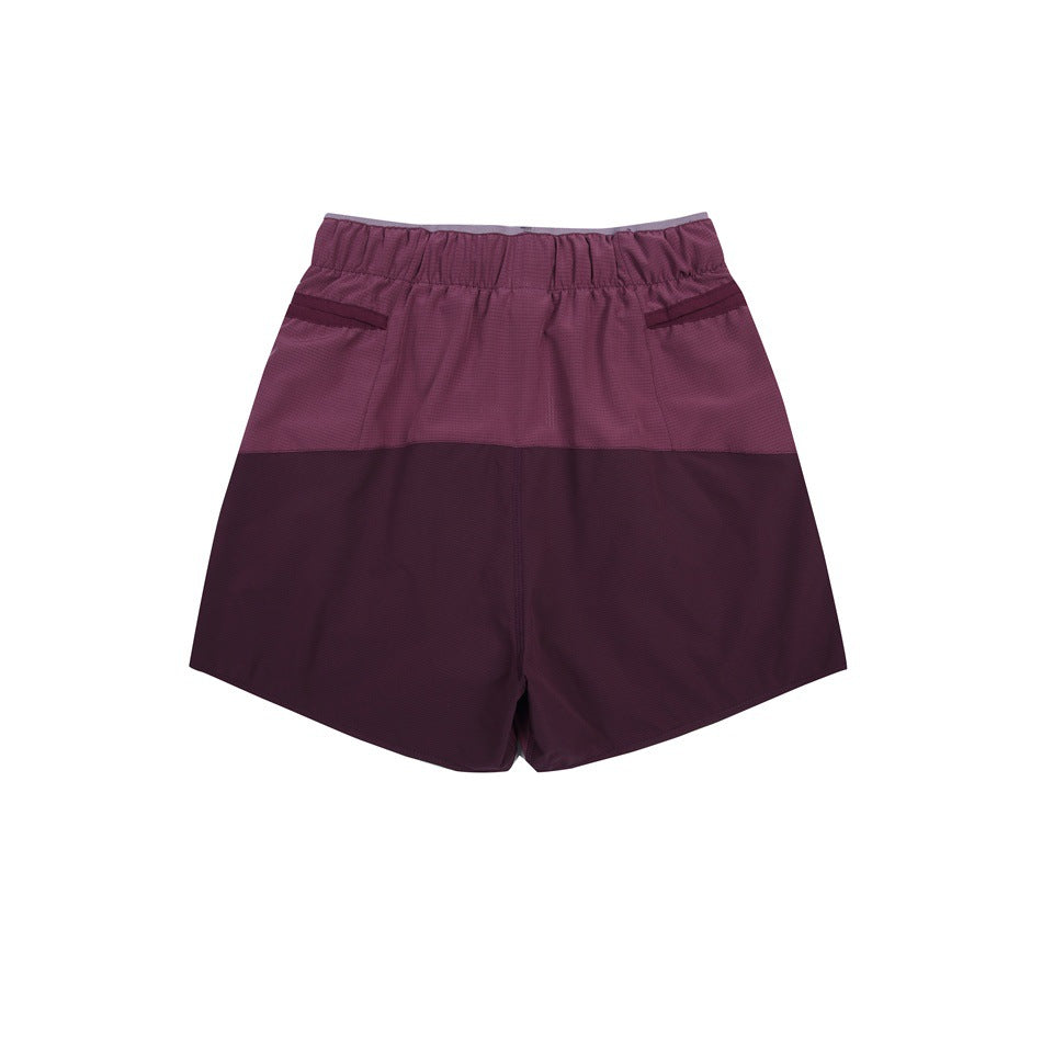 Back view of plum and dark burgundy color-block shorts with an elastic waist and two rear pockets.