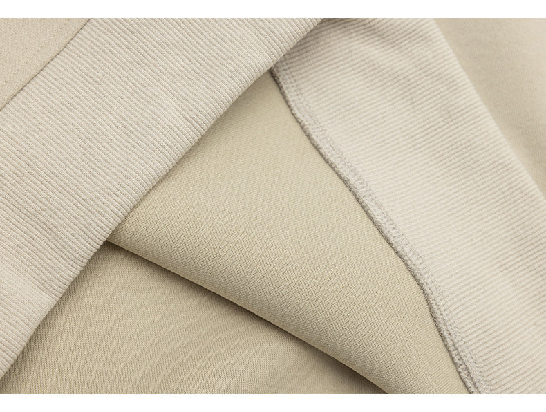 Close-up of beige sweatshirt fabric, ribbed trim, and an overlocked seam.