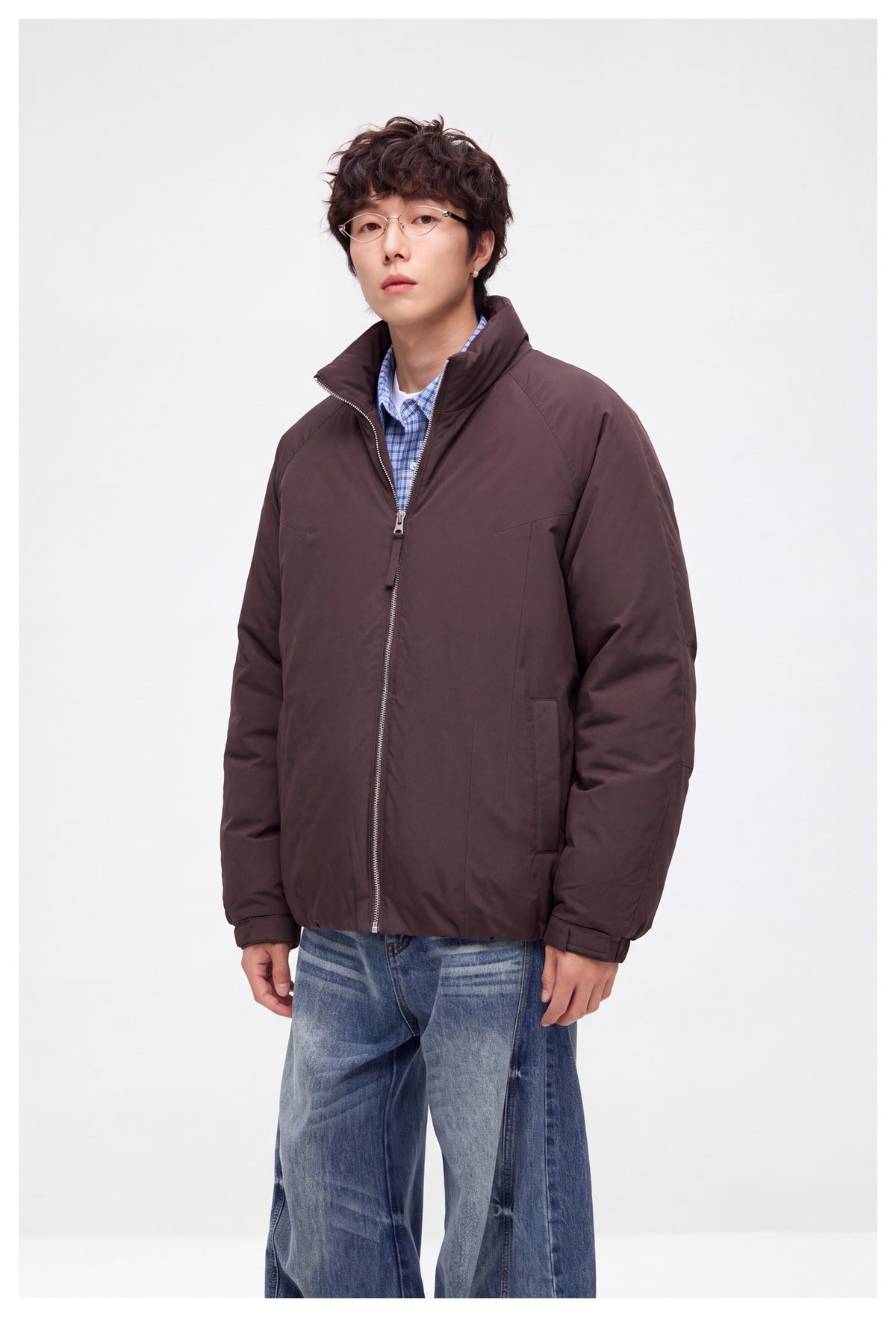 Three-quarter view of a model in a dark brown zip-front jacket with a raised collar and side pockets.