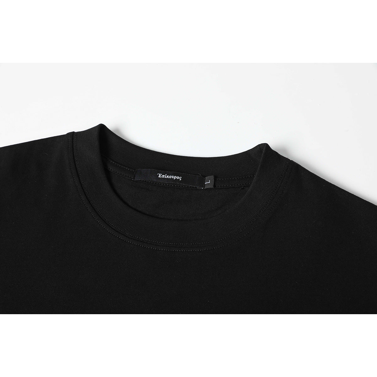 Close-up of a black crewneck shirt showing its ribbed collar, stitching, and sewn-in neck label.