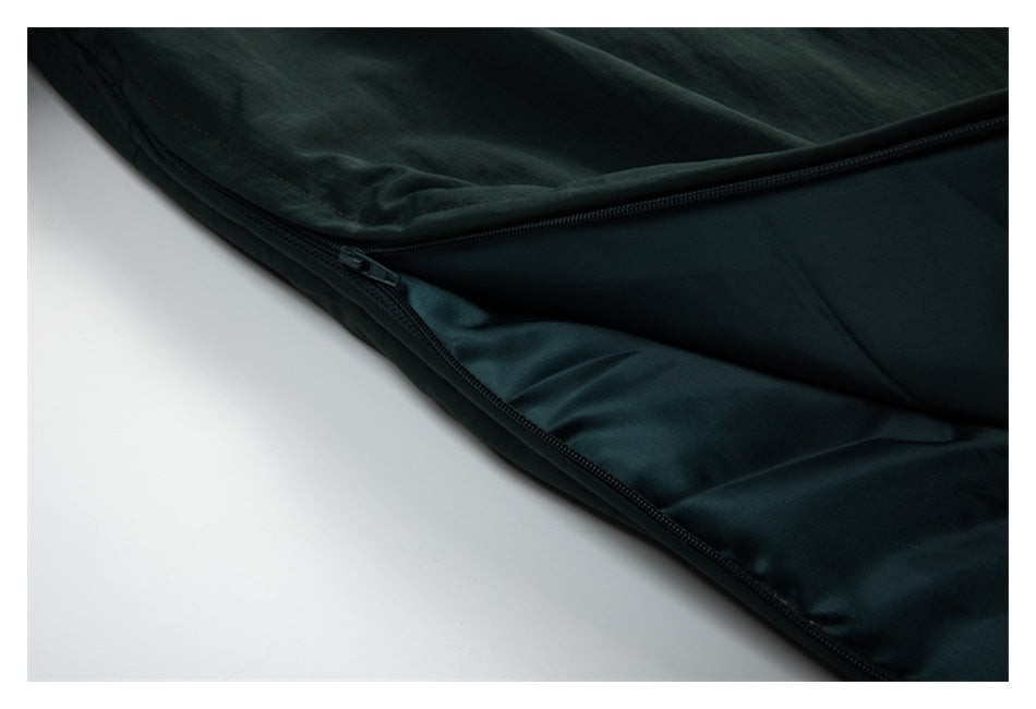 Close-up of dark green garment fabric with a diagonal zipper and seam.