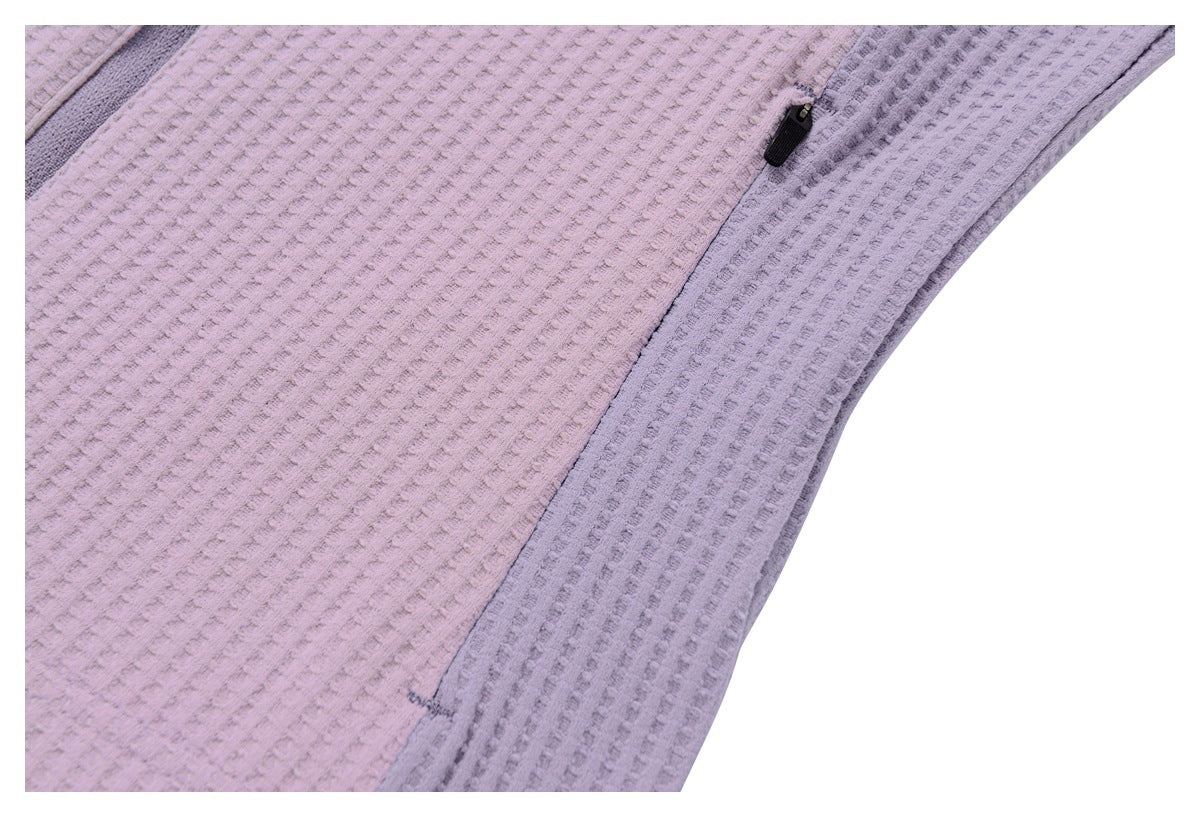 Close-up of a vertical pocket zipper and gray side panel on a mauve textured jacket.
