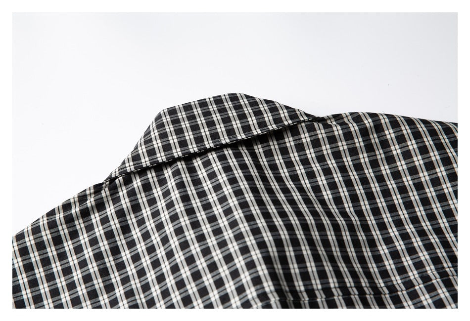 Close-up of the collar and shoulder of a black-and-white plaid shirt laid flat.