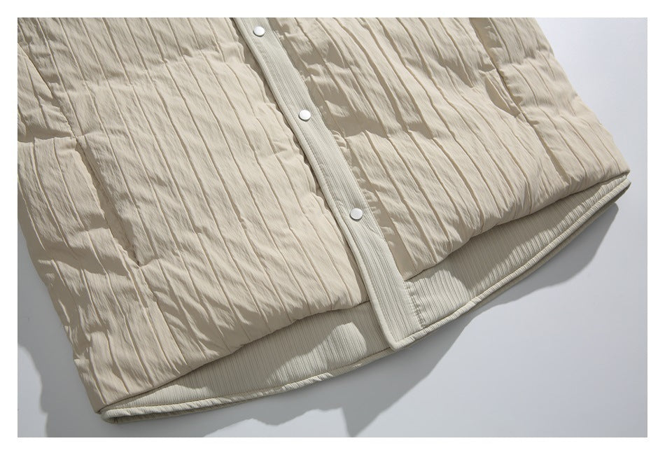 Close-up of a cream jacket’s crinkled panels, snap-button placket, and ribbed hem.