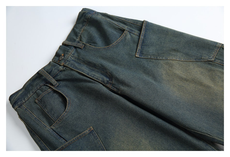 Dark indigo jeans laid flat, with front pockets, belt loops and orange contrast stitching visible.