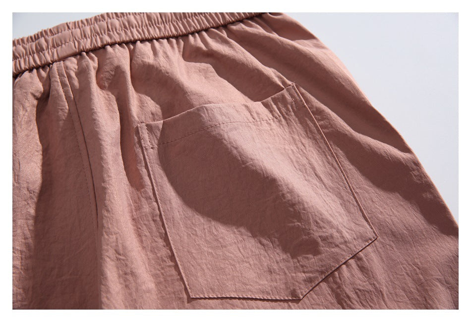 Close-up of dusty rose shorts with an elastic waistband and a large angled patch pocket.