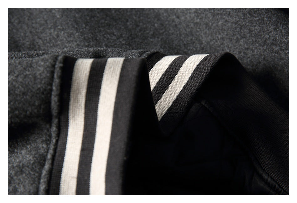Close-up of a charcoal coat sleeve and black ribbed cuff with two cream stripes.