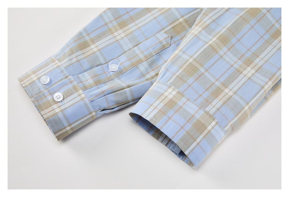 Close-up of two buttoned cuffs on a light blue, beige, and white plaid shirt.