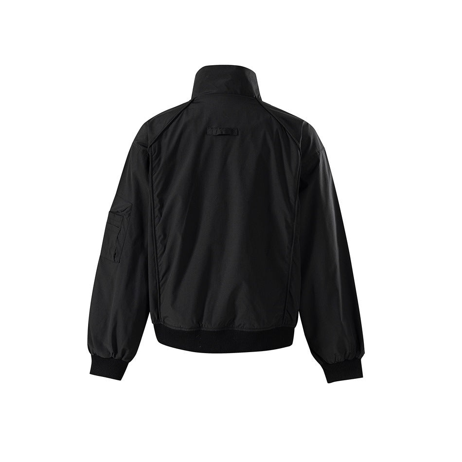 Back view of a black high-collar jacket with raglan seams, a sleeve pocket, and ribbed cuffs and hem.