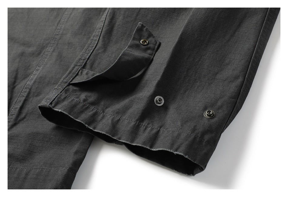 Close-up of dark charcoal pants showing a snap-fastened cuff and stitched hem.