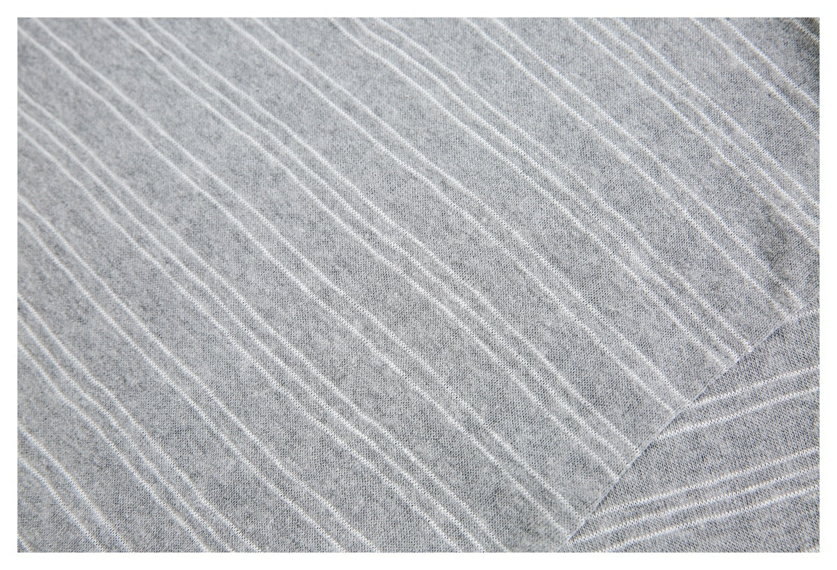 Close-up of gray knit fabric with narrow white diagonal stripes and a folded edge.
