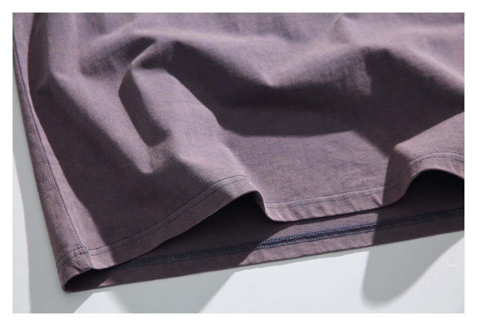 Close-up of a muted mauve garment hem with double stitching and an overlocked inner edge.