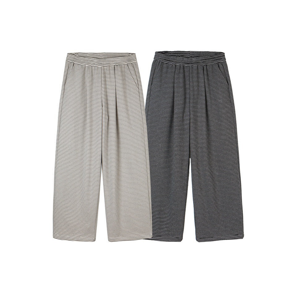 Two flat-lay pairs of wide-leg striped pants: one cream with dark stripes and one dark with light stripes.