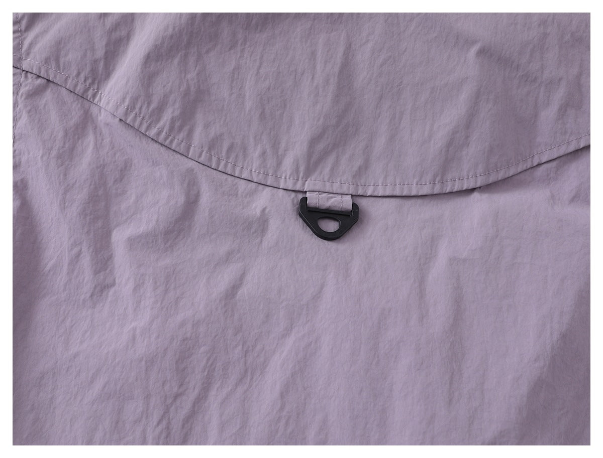 Close-up of lavender fabric with a curved stitched flap and a small black plastic loop clasp.