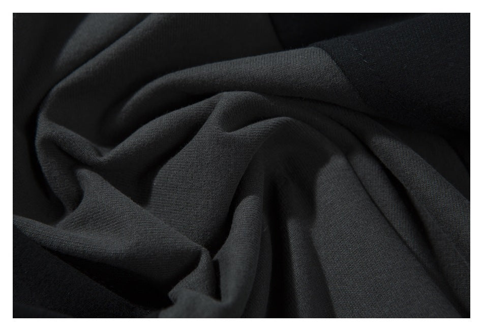 Close-up of gathered charcoal and black shirt fabric showing its surface texture and folds.